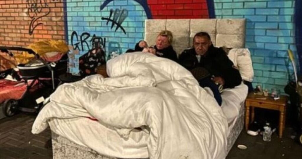 Man and pregnant woman living in a bed next to busy roundabout