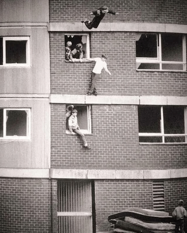 Children bouncing on worn out mattresses. England, 1980s.