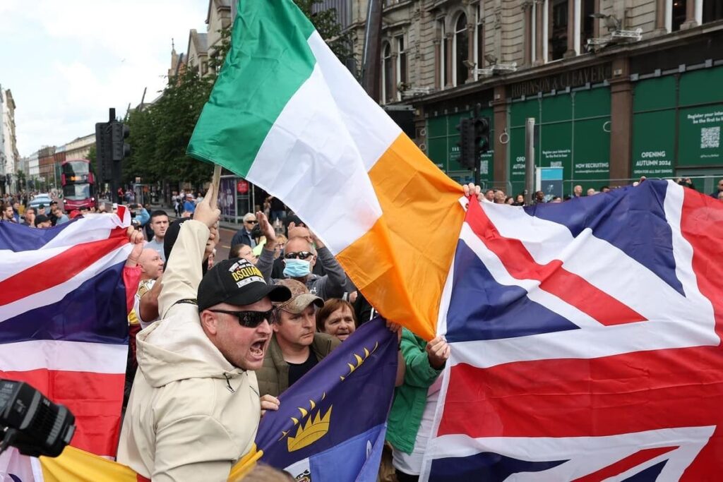 Union flags and Irish flags are flown side by side at anti immigrant protest in Belfast city centre