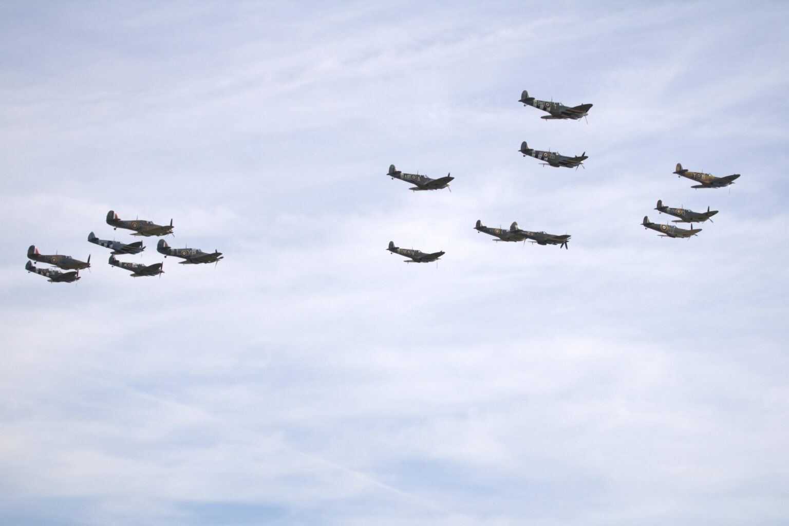 Battle of Britain Day. Mixed flight of 15 planes, Hurricanes and Spitfires flying over Duxford, UK.