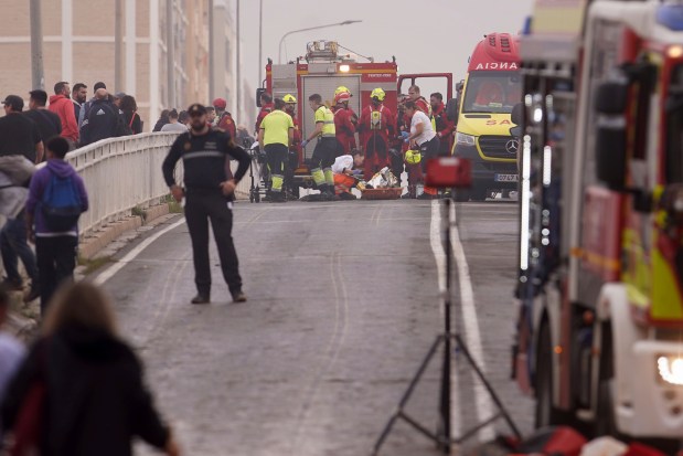 Emergency crews surround the body of a person on the ground after being rescued from the floods in Valencia, Spain, Wednesday, Oct. 30, 2024. (AP Photo/Alberto Saiz)