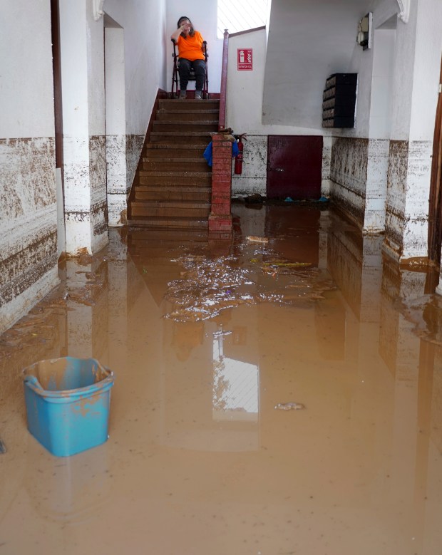 A woman in a wheelchair reacts as she looks around her flooded house in Valencia, Spain, Wednesday, Oct. 30, 2024. (AP Photo/Alberto Saiz)