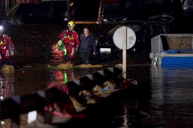 Residents, accompanied by firefighters, walk through flooded streets in Valencia, Spain, Wednesday, Oct. 30, 2024. (AP Photo/Alberto Saiz)