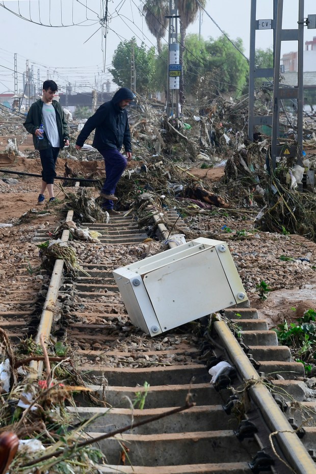 Residents walk among debris on a rail track following flood in Picanya, near Valencia, eastern Spain, on October 30, 2024. Floods triggered by torrential rains in Spain's eastern Valencia region has left 51 people dead, rescue services said on October 30. (Photo by Jose Jordan / AFP) (Photo by JOSE JORDAN/AFP via Getty Images)