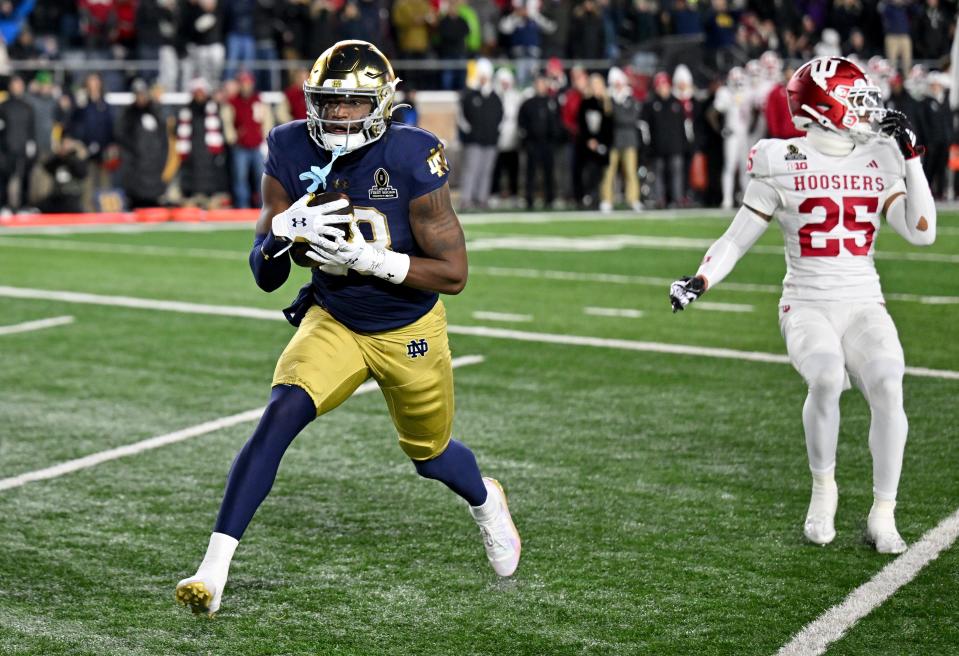 Dec 20, 2024; Notre Dame, Indiana, USA; Notre Dame Fighting Irish wide receiver Jayden Thomas (83) catches a touchdown against Indiana Hoosiers defensive back Amare Ferrell (25) during the first quarter at Notre Dame Stadium. Mandatory Credit: Matt Cashore-Imagn Images