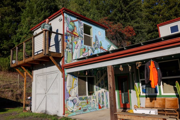 Solar Punk Farms cofounder Spencer Scott stands on the balcony, which features a mural on the facade in Guerneville, Calif., on Thursday, Dec. 5, 2024. (Ray Chavez/Bay Area News Group)
