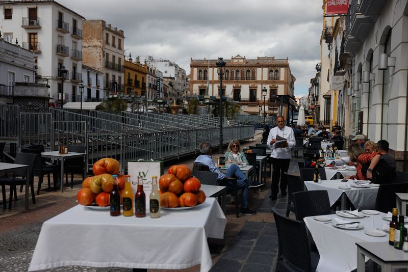 © Reuters. FILE PHOTO: A waiter serves tourists at the terrace of a restaurant in front of an official stand, installed to watch the Holy Week processions, in Ronda, Spain, March 14, 2024. REUTERS/Jon Nazca/File Photo © Reuters. FILE PHOTO: A waiter serves tourists at the terrace of a restaurant in front of an official stand, installed to watch the Holy Week processions, in Ronda, Spain, March 14, 2024. REUTERS/Jon Nazca/File Photo