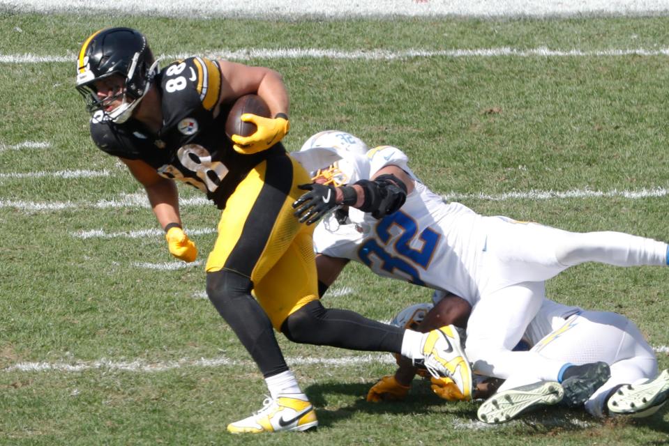 Sep 22, 2024; Pittsburgh, Pennsylvania, USA; Pittsburgh Steelers tight end Pat Freiermuth (88) runs after a catch as Los Angeles Chargers safety Derwin James Jr. (bottom) and safety Alohi Gilman (32) tackle during the third quarter at Acrisure Stadium. Pittsburgh won 20-10. Mandatory Credit: Charles LeClaire-Imagn Images
