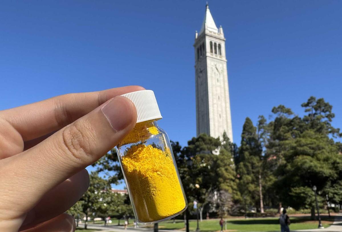 A vial of COF-999, which is yellow, with UC Berkeley’s landmark campanile in the background.