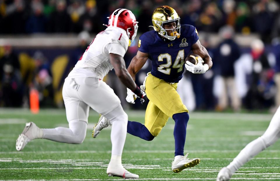 Dec 20, 2024; Notre Dame, Indiana, USA; Notre Dame Fighting Irish running back Jadarian Price (24) runs against Indiana Hoosiers defensive back Shawn Asbury II (1) during the first quarter at Notre Dame Stadium. Mandatory Credit: Matt Cashore-Imagn Images