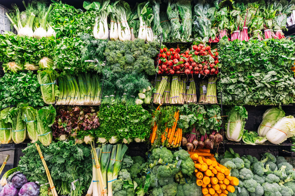 A grocery store shelf showcasing various vegetables like lettuce, carrots, broccoli and other produce.