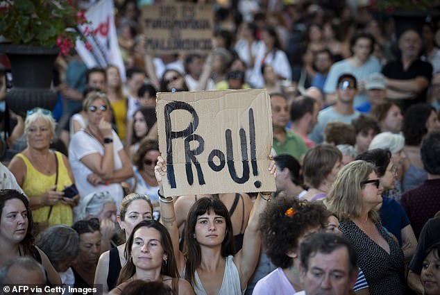 A woman holds a placard which reads as 'Enough!' as they take part in a demonstration to protest against overtourism and housing prices on the island of Mallorca in Palma de Mallorca on July 21, 2024