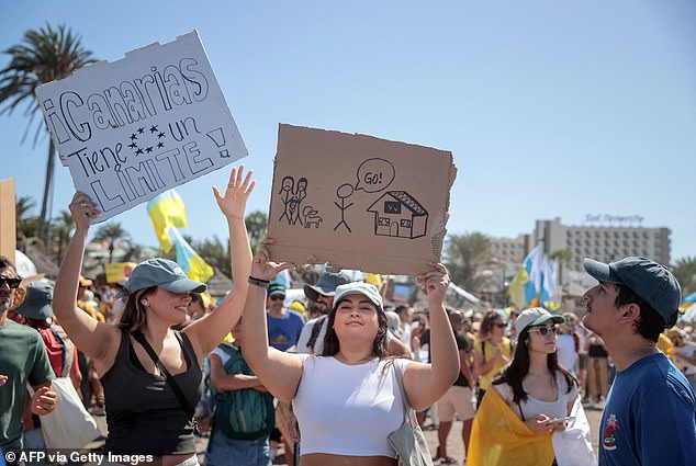 A protester holds a sign reading "Canary Islands have a limit" as thousands march on Las Americas beach during a demonstration against mass tourism, in Arona on the Spanish Canary island of Tenerife, on October 20, 2024