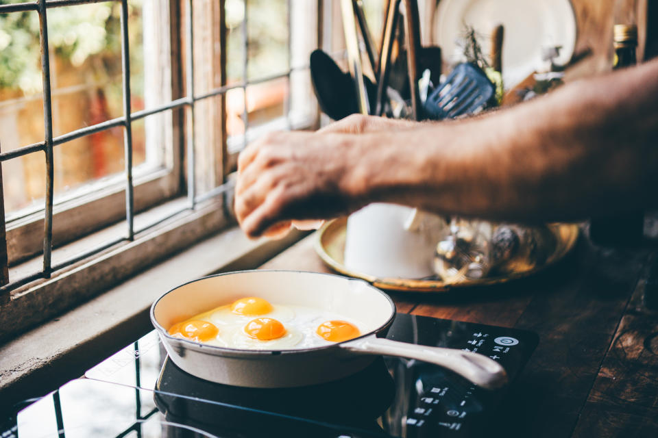 A man fries eggs at home in his kitchen.