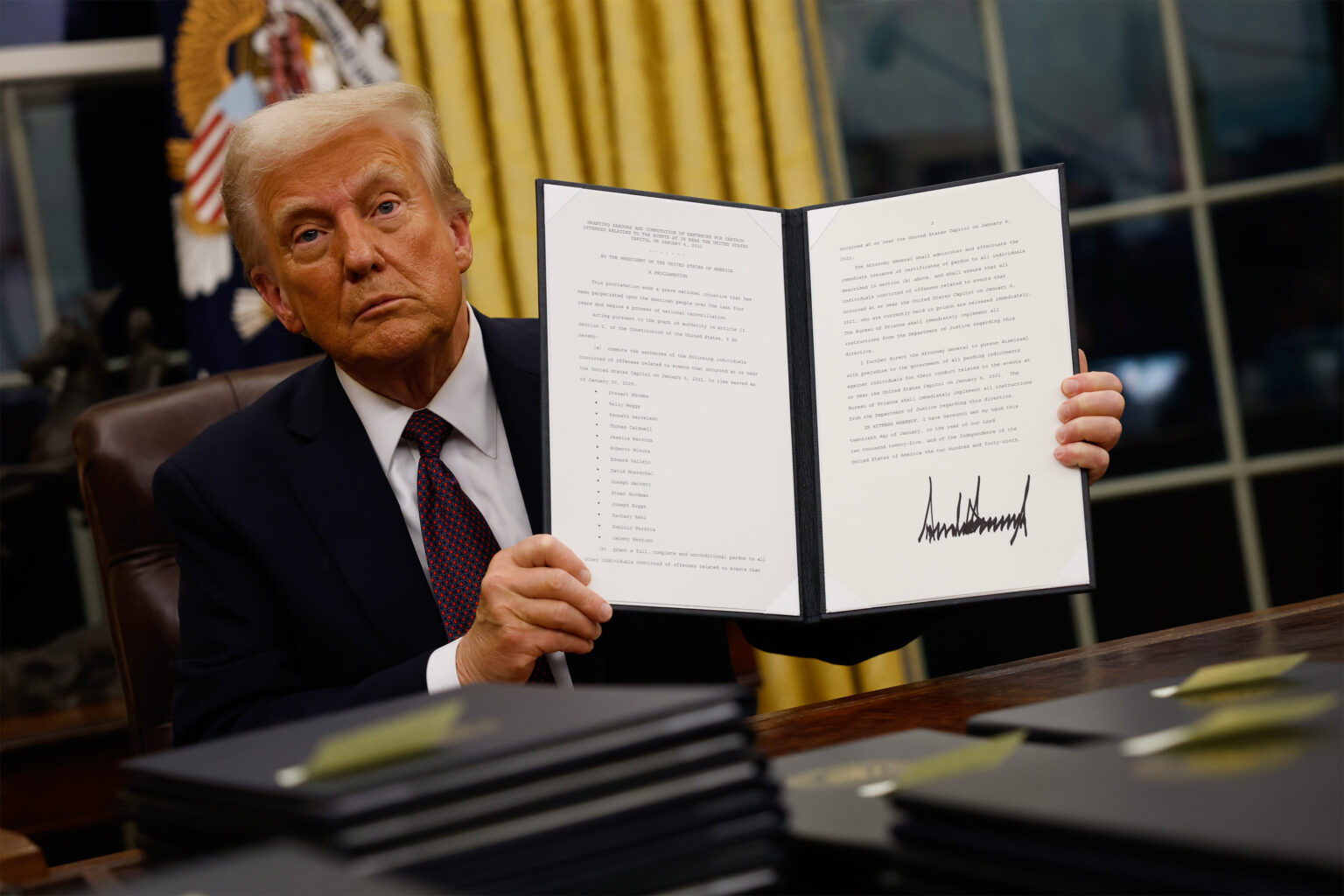 What Trump’s Executive Order on Gender Means for Trans Health Care A photo of President Donald Trump holding up a signed executive order to the camera.