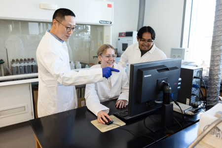 Professor working with students at computer in lab. 