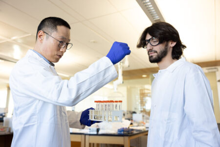 Professor and student looking at test tube.