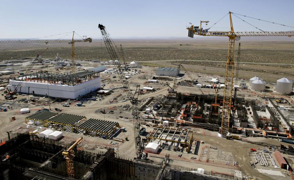 Cranes above a large industrial site with dusty shrubland in the background