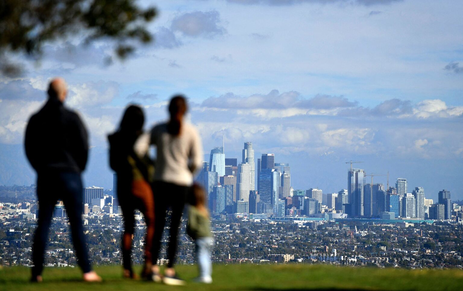 10 Ways We’ll Fight the Trump Administration to Protect Our Environment A group of adults and children in the foreground look out at downtown Los Angeles on a partly cloudy day with little to no haze.