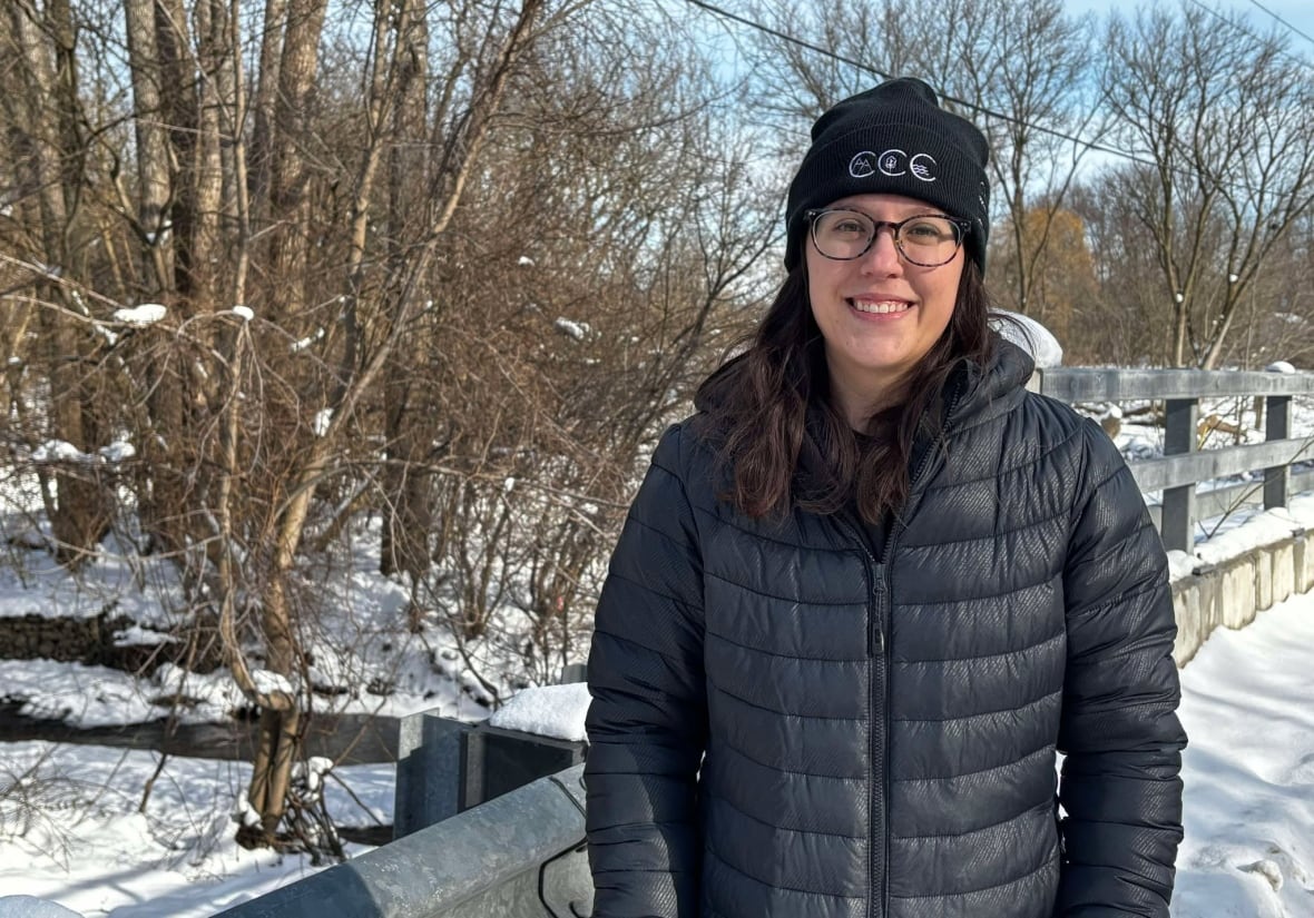 A woman stands next to a river.