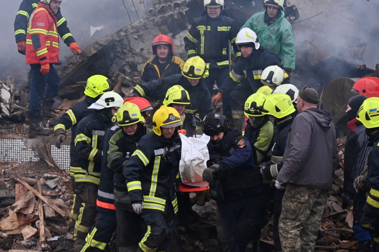 Firefighters carry the body of a civilian following a missile strike in Poltava.