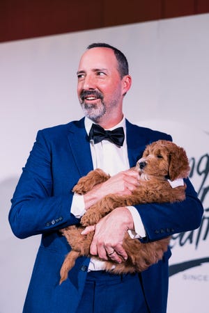 Tony Hale holds a goldendoodle sponsored by Forever My Doodle for the Live Auction at the Young Actors Theatre 50th anniversary gala on Feb. 1, 2025.