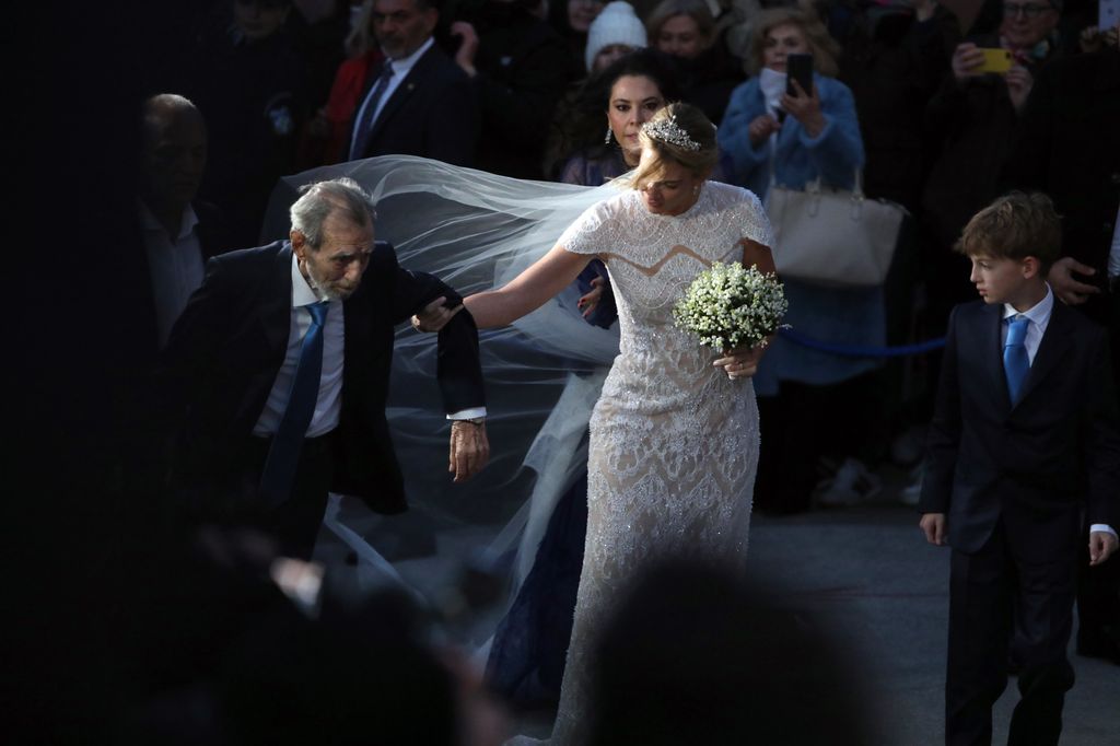 Chrysi Vardinogianni (C) is accompanied by her father Giorgos Vardinogianni (L) as they arrive for her wedding with Nikolaos De Grece at the Church of Agios Nikolaos Rangavas in Athens