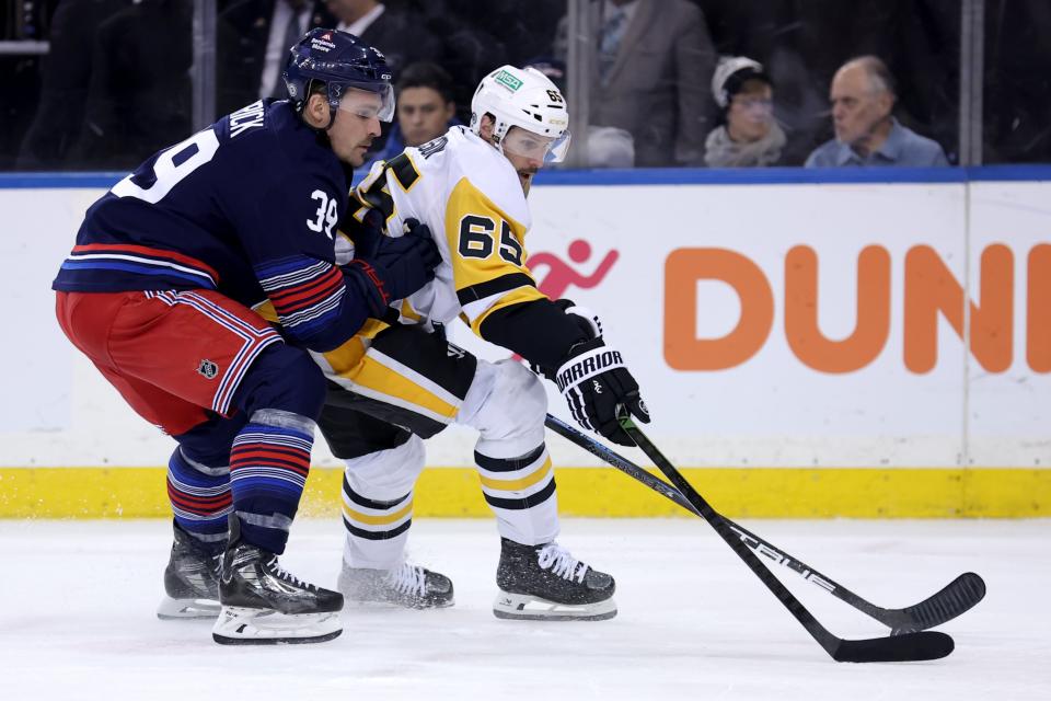Feb 7, 2025; New York, New York, USA; Pittsburgh Penguins defenseman Erik Karlsson (65) fights for the puck against New York Rangers center Sam Carrick (39) during the second period at Madison Square Garden. (Brad Penner-Imagn Images)