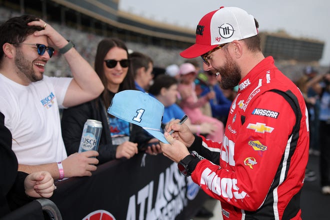 HAMPTON, GEORGIA - FEBRUARY 23: Tyler Reddick, driver of the #45 Xfinity Mobile Toyota, signs autographs for a NASCAR fan prior to the NASCAR Cup Series Ambetter Health 400 at Atlanta Motor Speedway on February 23, 2025 in Hampton, Georgia. (Photo by Jonathan Bachman/Getty Images)