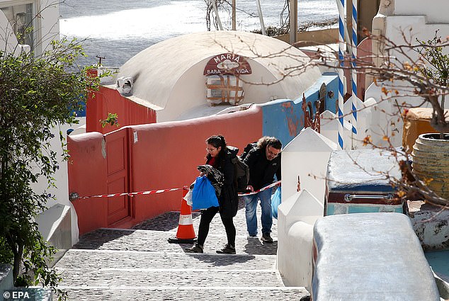 People cross a police cordon as they evacuate their home in the village of Oia on Santorini island, Greece, 05 February 2025