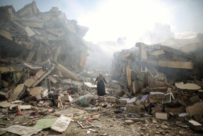 A woman stands amid rubble in al-Zahra after an Israeli airstrike, October 19, 2023.