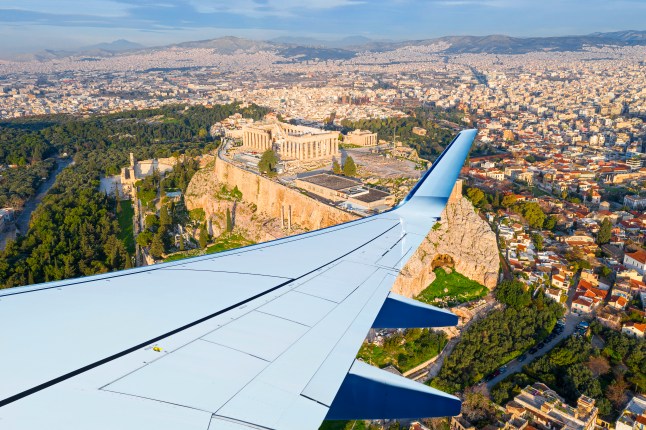 An aerial view of the Acropolis of Athens in Greece and an aeroplane wing.