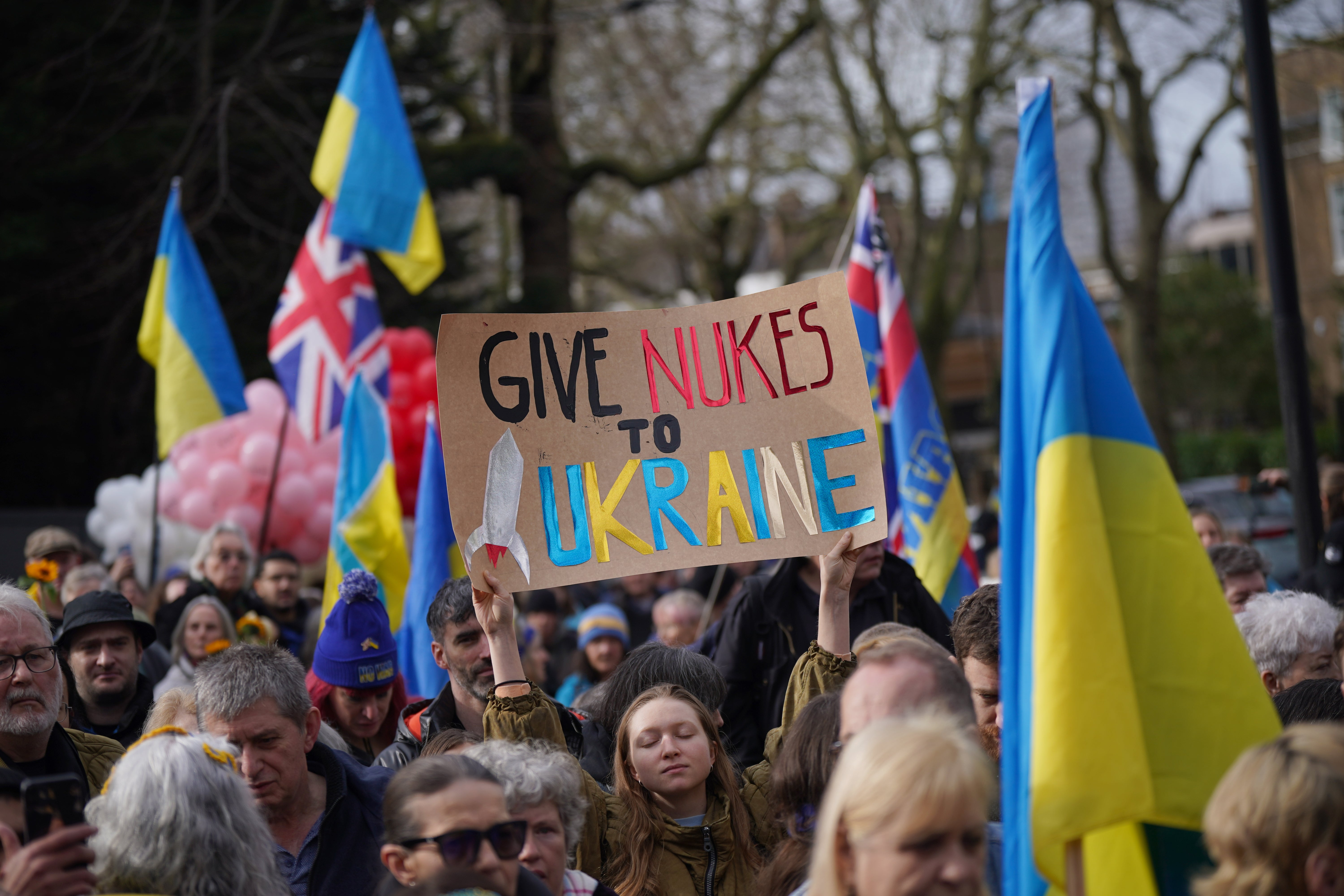 A woman holds a ‘Give nukes to Ukraine’ placard on a march through London