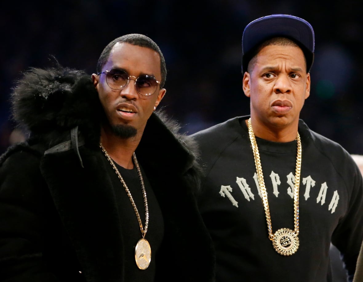 Two people are seen standing on the sidelines of a basketball game.