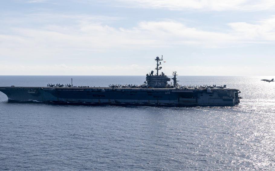 The carrier USS Harry S. Truman, with a jet close behind, sails through the sea.