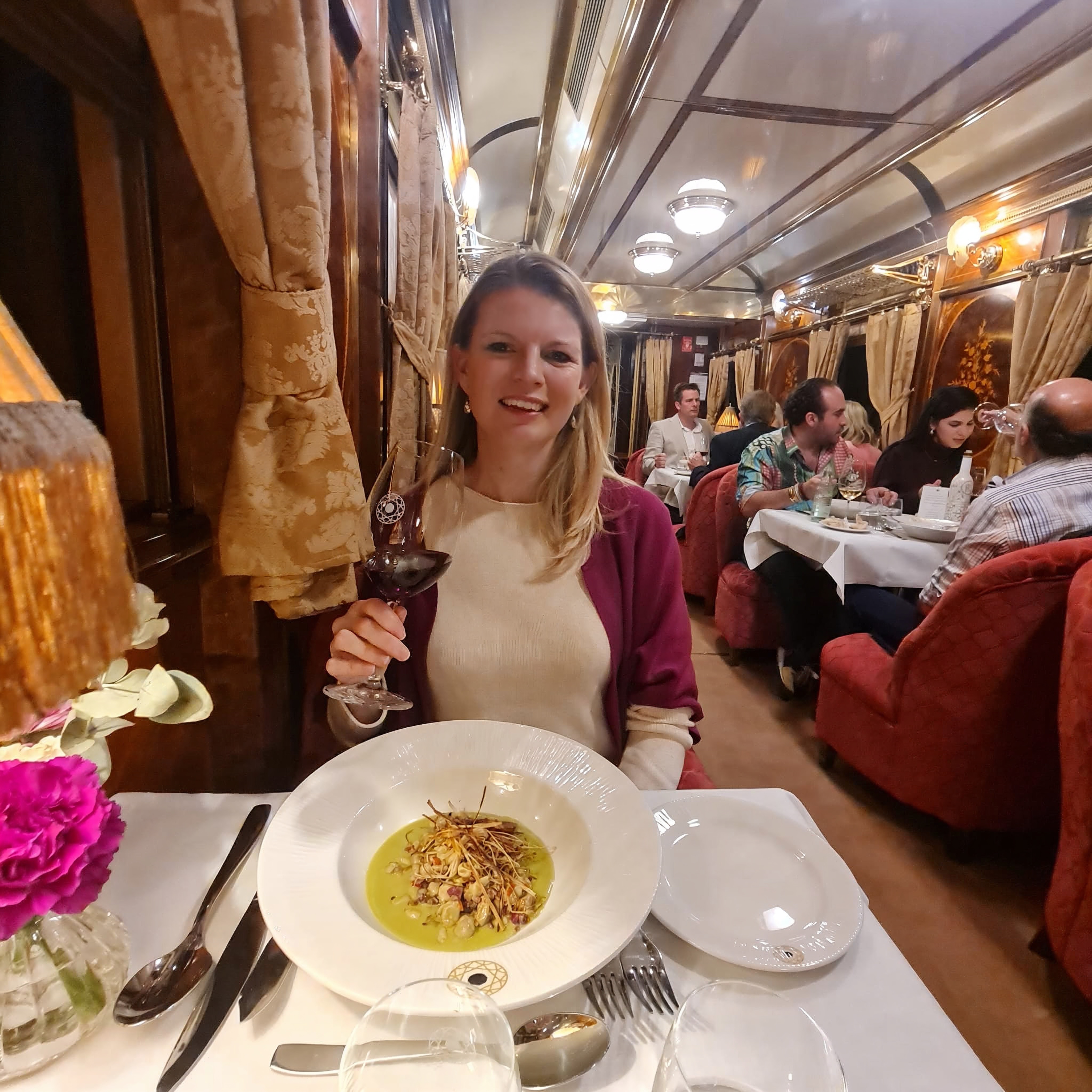 Woman enjoying a meal and wine on a luxury train.