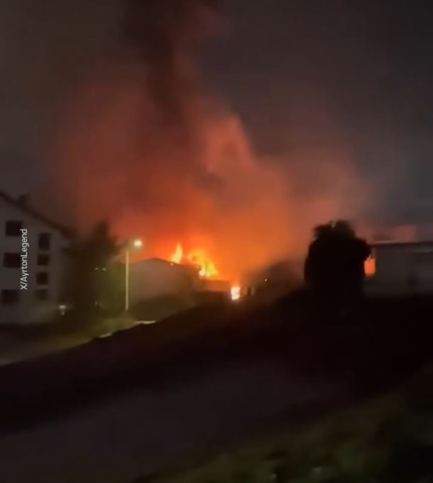 Nighttime view of a large fire engulfing a building.