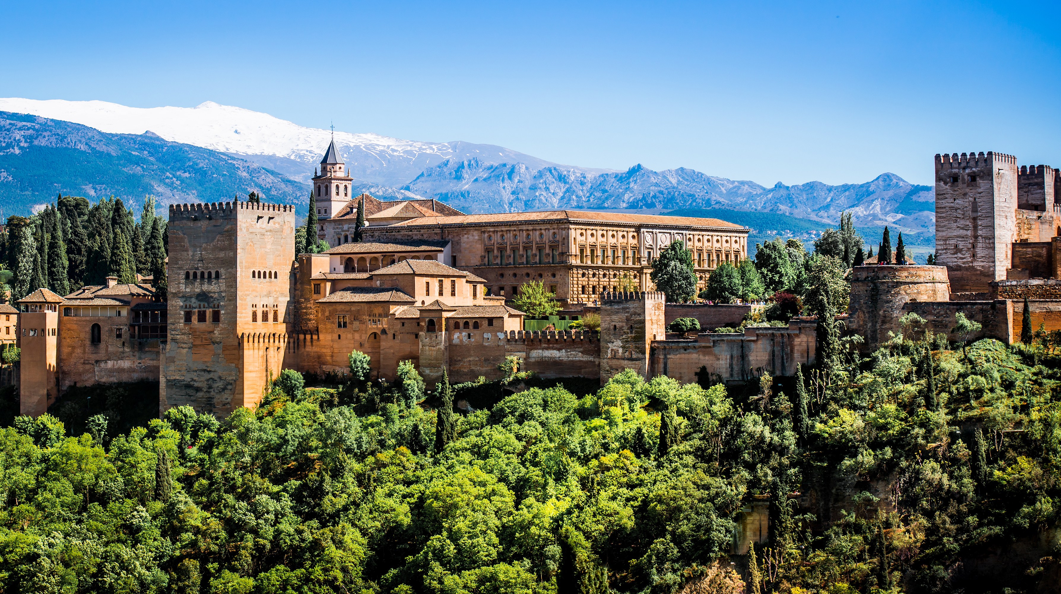 The Alhambra palace in Granada, Spain, with snow-capped mountains in the background.