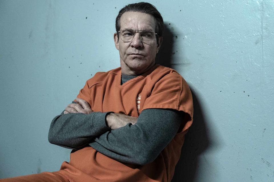 Dennis Quaid dressed in orange with his arms folded