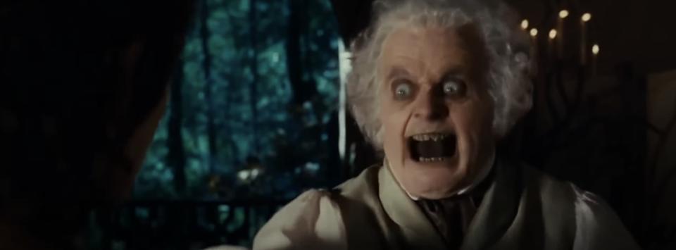 Elderly character with wide eyes and open mouth, appearing startled or intense, in a dark, atmospheric scene from a movie or TV show