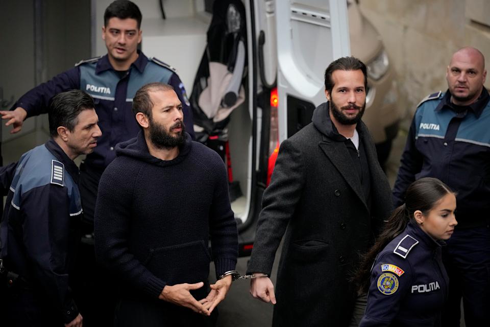 Andrew Tate, center, handcuffed to his brother, Tristan Tate, in Bucharest