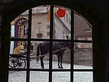 Horse pulling a cart seen through barred gate, creating a vintage or historical feel
