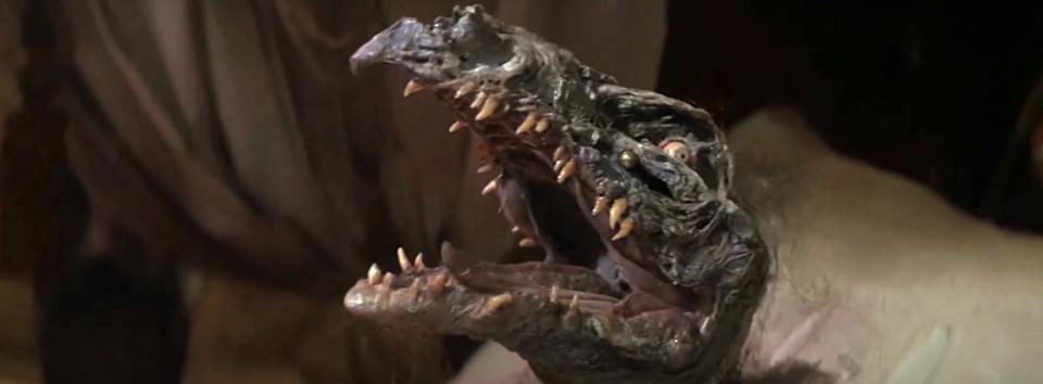Animatronic creature with sharp teeth and a gaping mouth, featuring in a movie or TV show scene