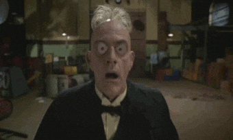 A man wearing a suit and bow tie looks shocked, with exaggerated bulging eyes in a dramatic or comedic setting