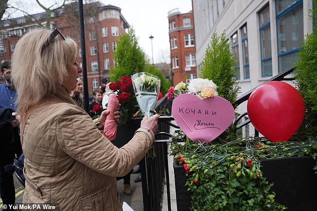 A mourner places flowers outside the North Macedonian Embassy in London on Sunday ahead of a vigil for those lost in the nightclub fire