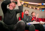 From left, Jon Vogel, son Hank Vogel, and Hank's friend Flynn Knox clap and cheer during a Portland Trail Blazers game in Portland, Ore., Feb. 22, 2025. Hank, who is blind, says that, before the Trail Blazers offered the OneCourt tactile device, these games were "boring" for him, because he often didn't know what was going on. 
