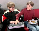 Hank Vogel shows friend Flynn Knox how to use the OneCourt device. The technology uses real-time data to translate the game into haptic vibrations for sports fans who are blind or low-vision.