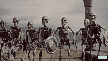 Animated skeletons wielding swords and shields march forward in a scene from a vintage film