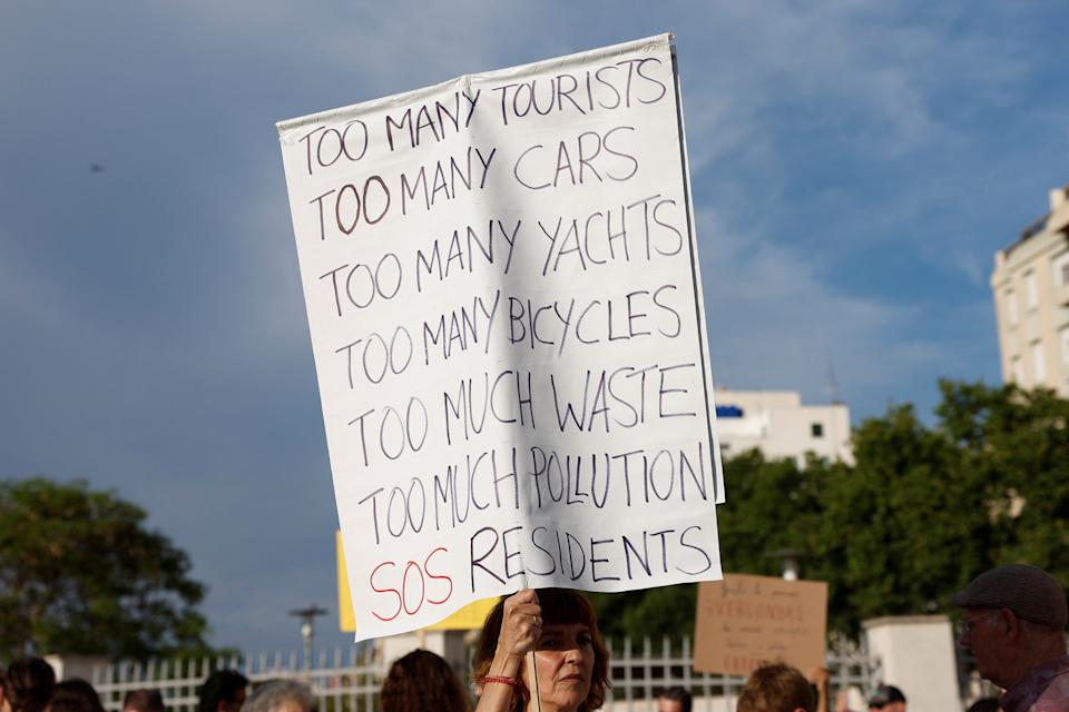 A demonstrator holds a sign during a protest against mass tourism and gentrification in the island ahead of summer season in Palma de Mallorca, Spain, May 25, 2024. REUTERS/Juan Medina
