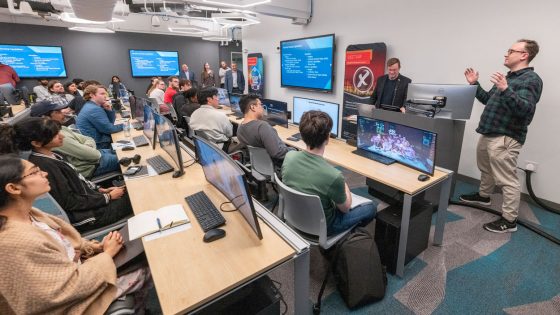 Torin Hovander speaking before standing room only crowd at UMSL YouthMappers' Off-Ramp Speaker Series event in the Geospatial Advanced Technology Lab
